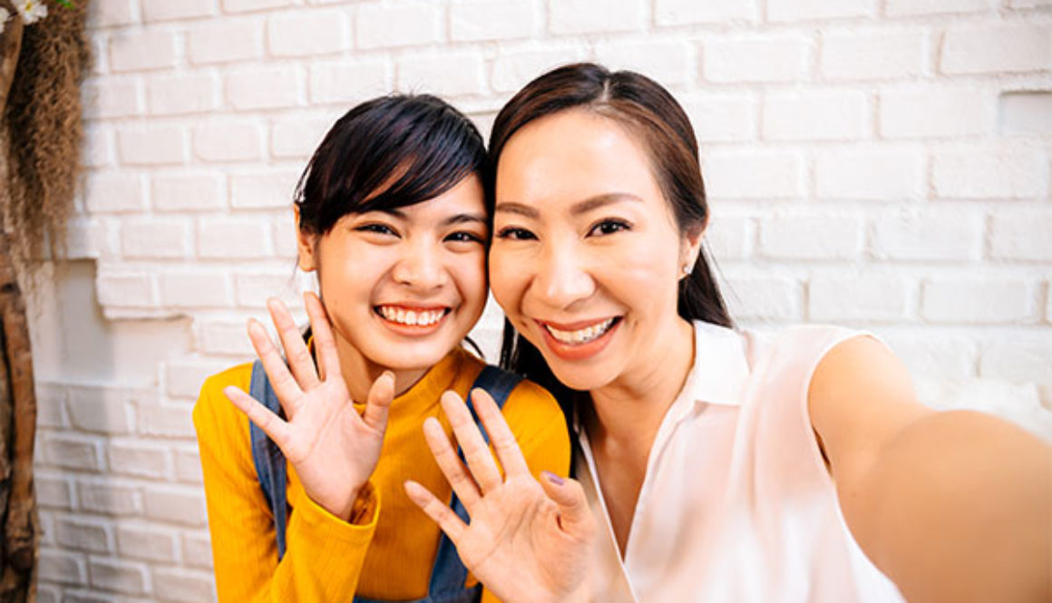 Face of smiling happy Asian teenage daughter and Asian middle-aged mother