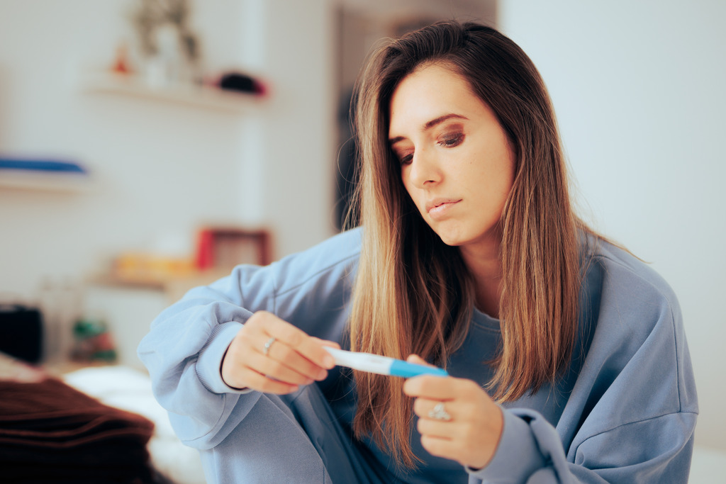 A Woman Examining a Pregnancy Test Wonders How to Test If a Woman is Infertile