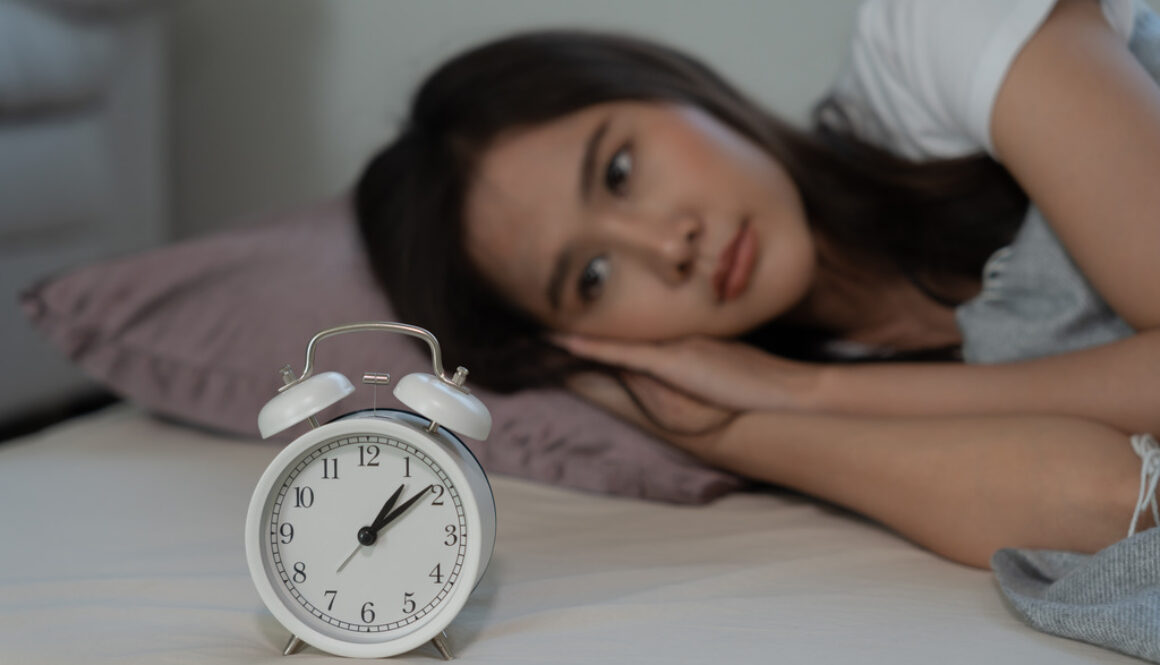 A Woman Laying On Her Side In Bed Looking At A Clock Can An OBGYN Help You With Hormones