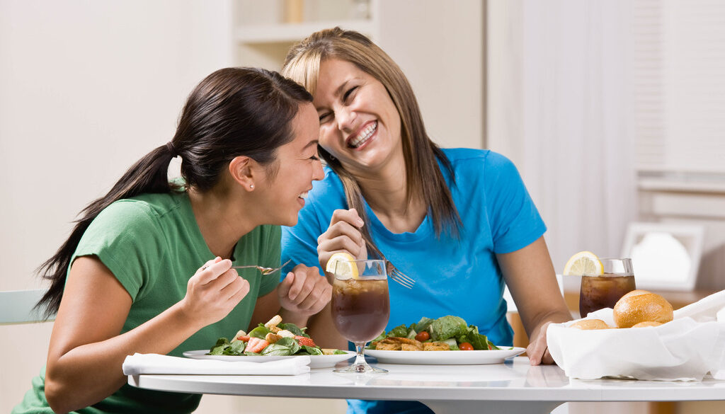 Two Women Laughing While Eating a Healthy Meal Nutrition and Women’s Health