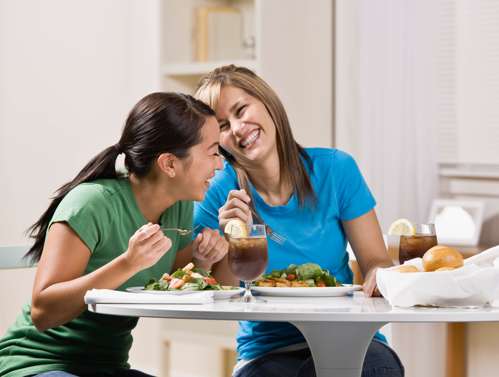 Two Women Laughing While Eating a Healthy Meal Nutrition and Women’s Health