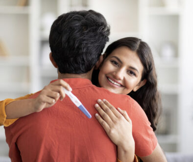Smiling Indian Woman Hugging Her Significant Other While Holding a Positive Pregnancy Test Trying to Get Pregnant