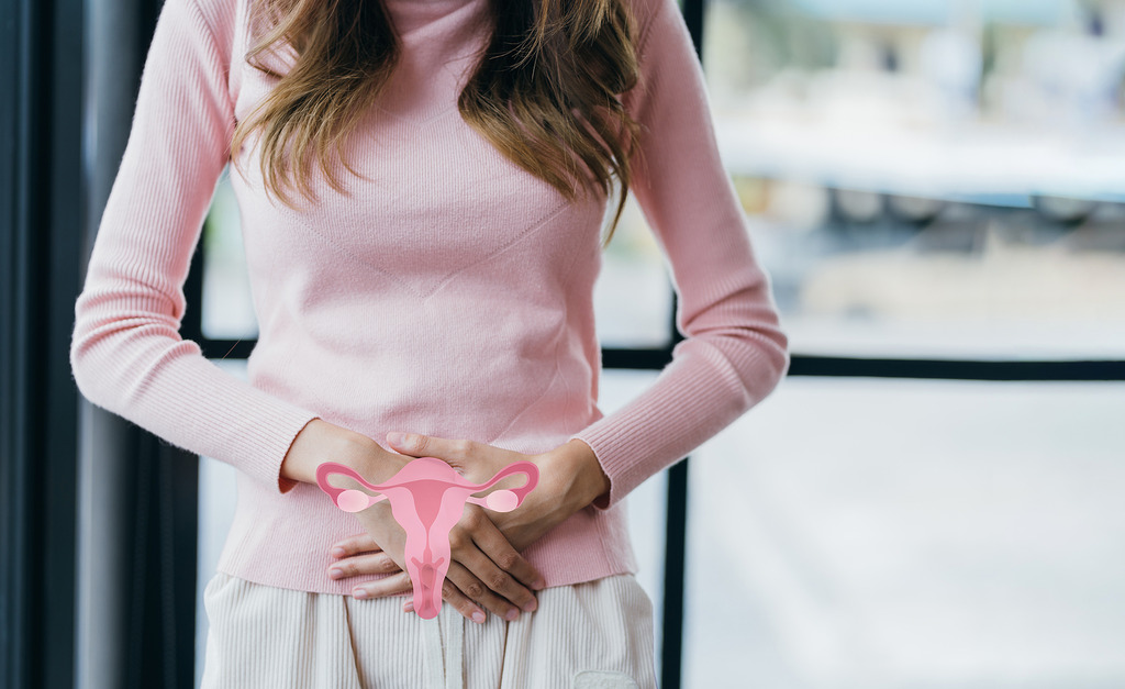Woman Holding Her Hands on Her Lower Stomach With a Cartoon Model of a Uterus Does PCOS Go Away